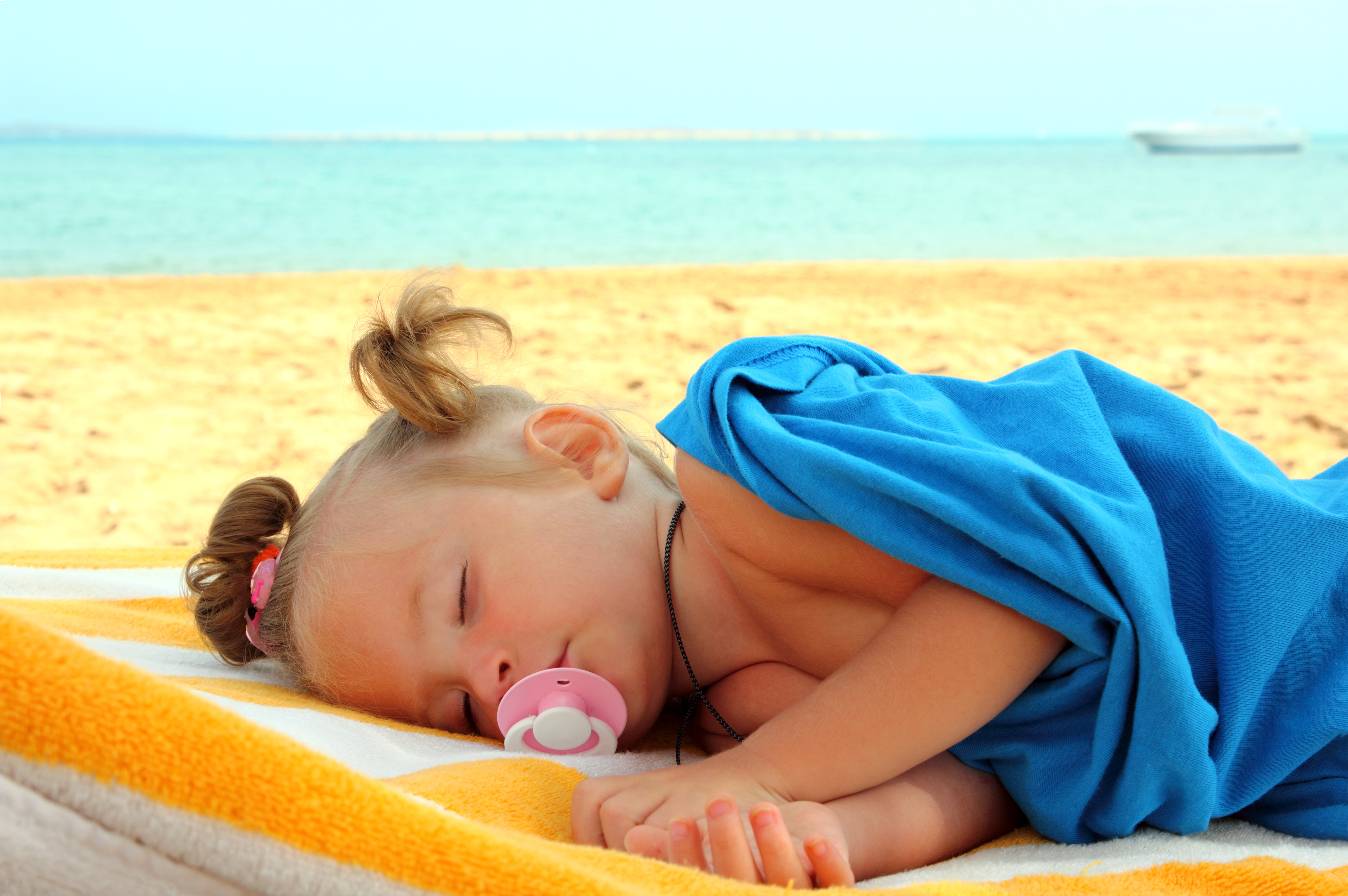 little girl sleeping on beach near sea