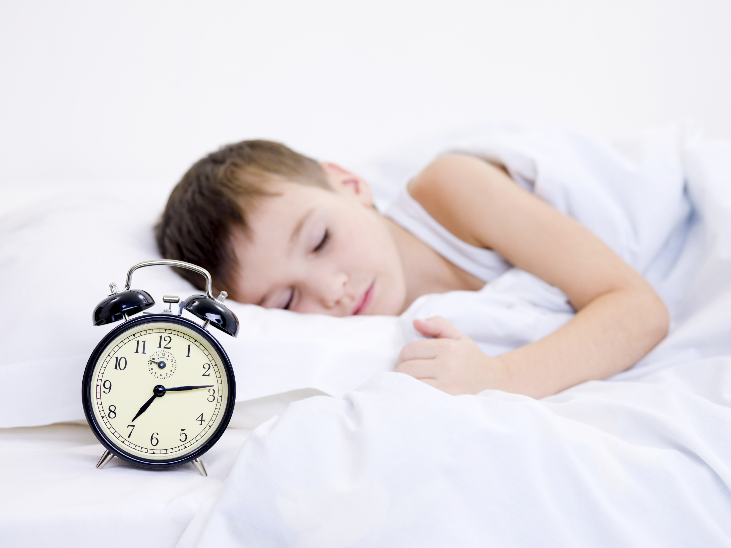 Little boy sleeping with alarm clock near his head