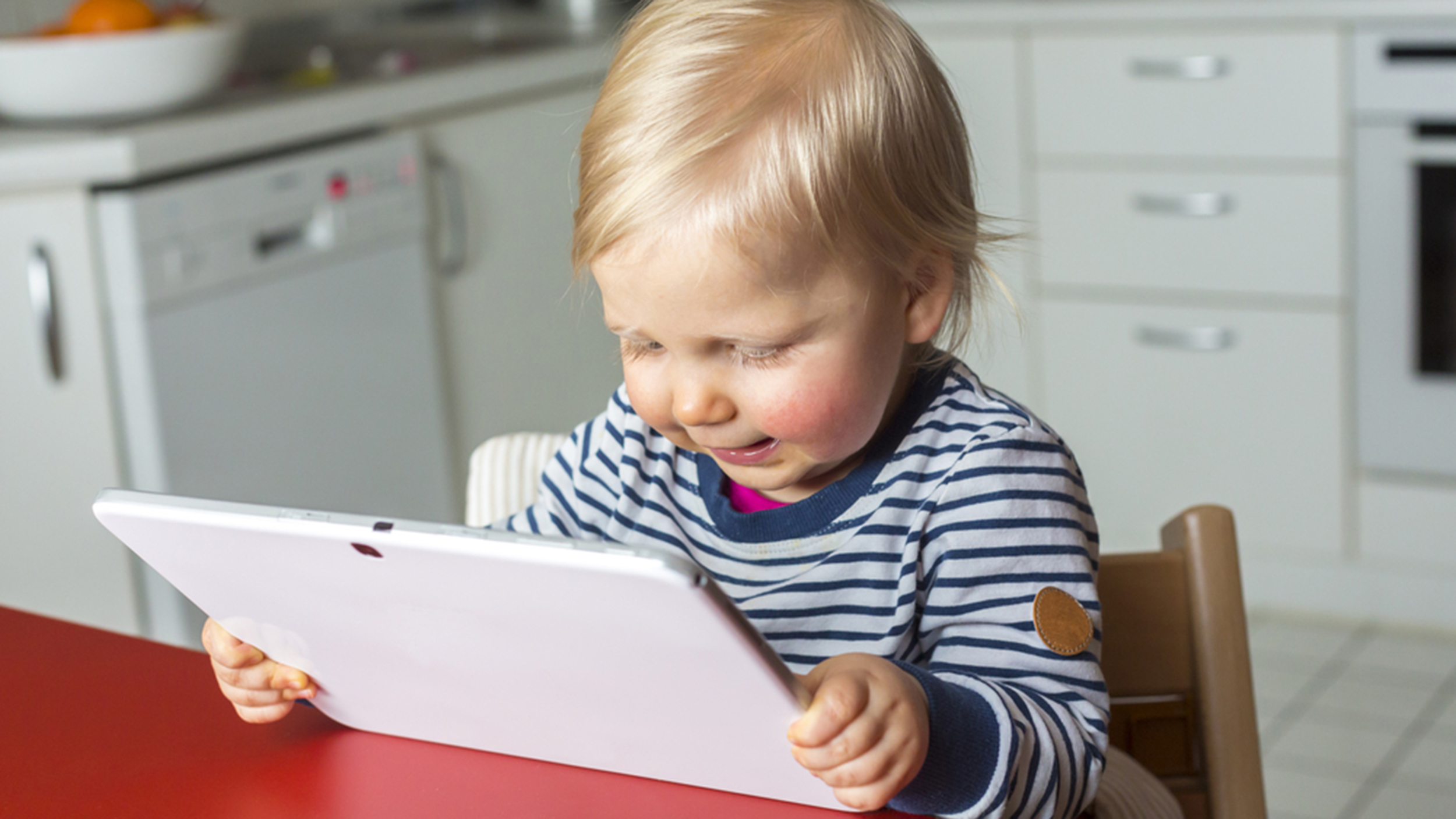 Toddler on a highchair reading a tablet pc; Shutterstock ID 242674822; PO: Brandon for Parents
