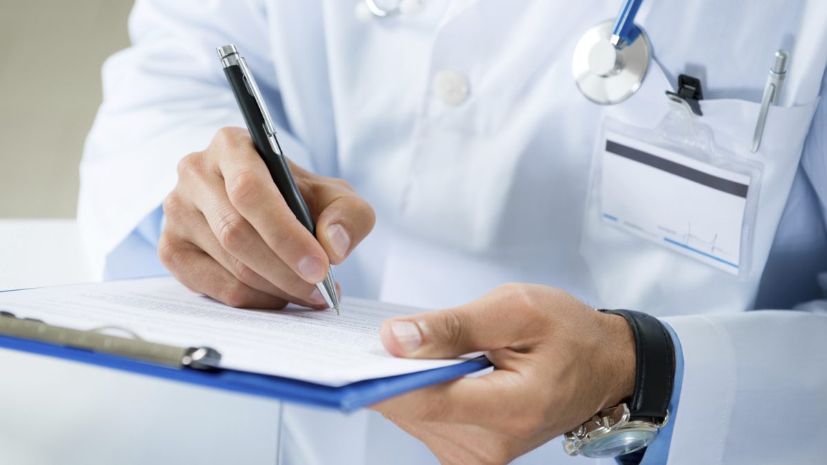 Close-up Of Male Doctor Filling The Medical Form