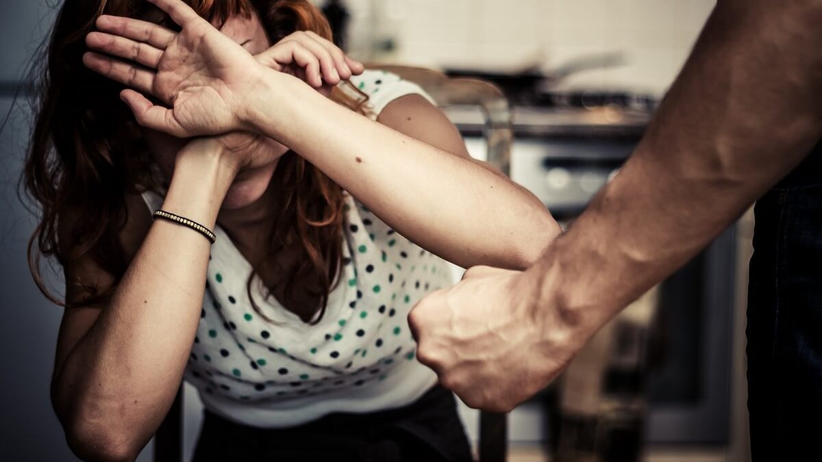 Woman is Covering Her Face In Fear Of Domestic Violence as her partner threatens her with his fist