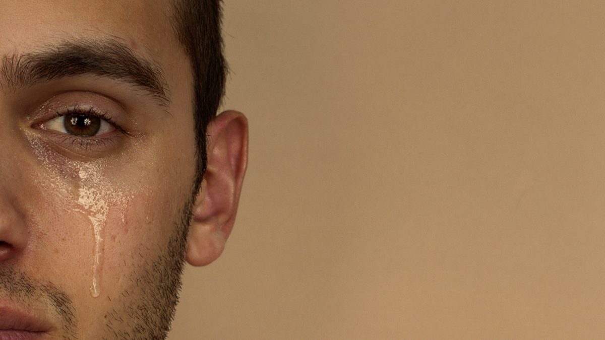 Young man with tear rolling down cheek, portrait, close-up